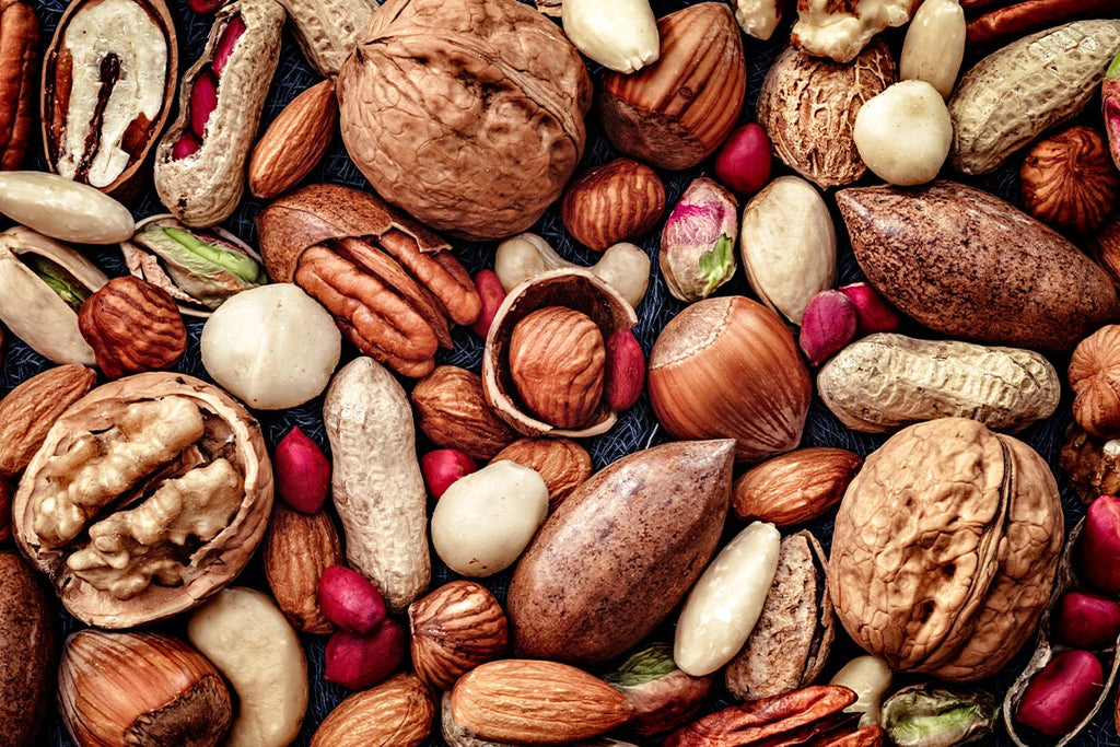 Frutta secca di stagione vista dall'alto: noci, mandorle pugliesi, pistacchi e nocciole, snack naturali della Dieta Mediterranea